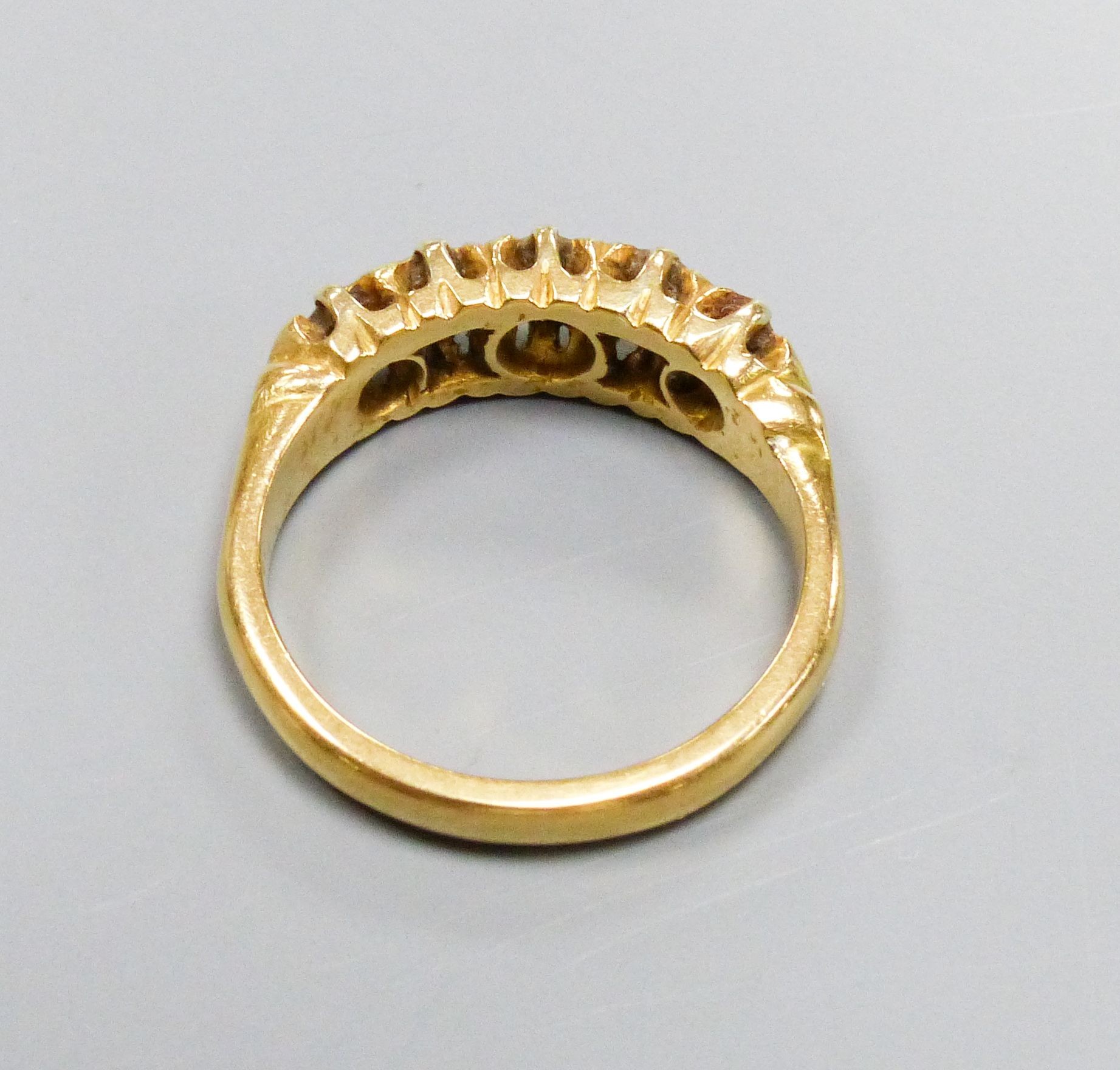 A five-stone diamond ring, 18ct yellow gold setting, claw-set with carved shoulders, size K, gross 5.5 grams.